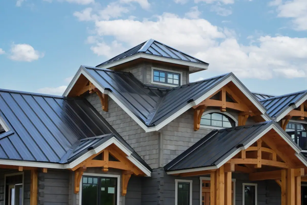 Modern house with gray siding and dark metal roof, featuring multiple peaked roofs and exposed wooden beams—expertly crafted by a leading roofing contractor in Monmouth County, NJ—set against a partly cloudy blue sky.